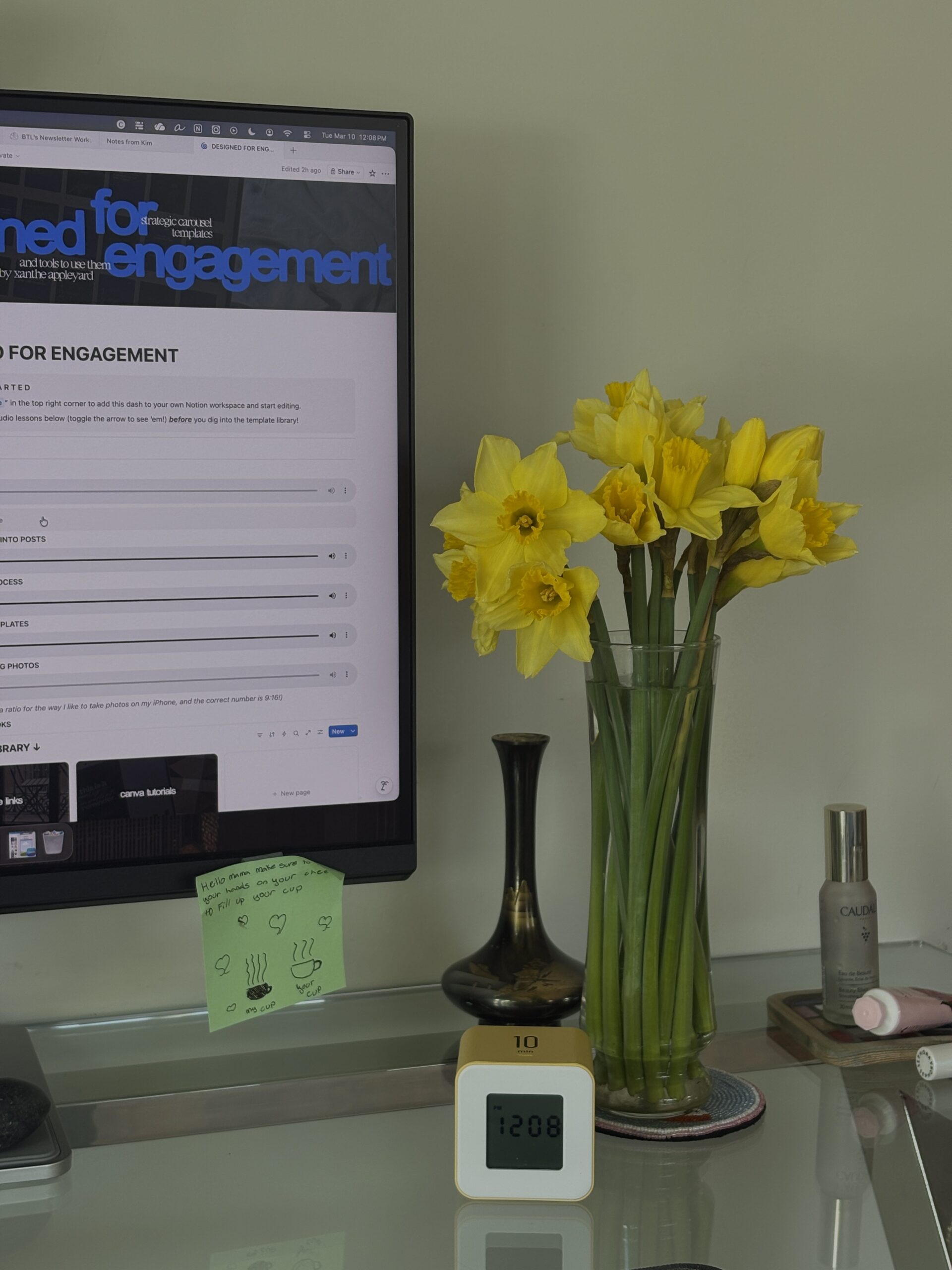 Desktop computer with Notion open, next to a vase of daffodils